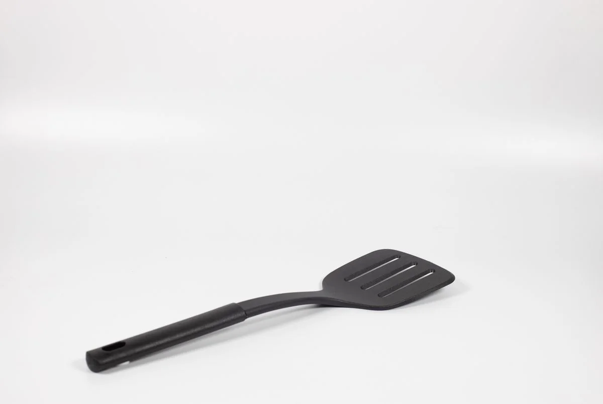 Simple black spatula utensil displayed on a white background with ample copy space.