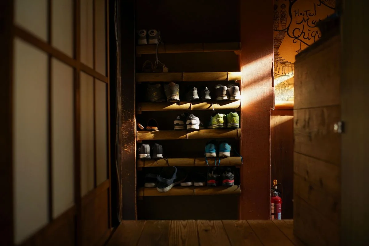 Warmly lit shoe rack featuring organized sneakers in a traditional Kyoto residence.
