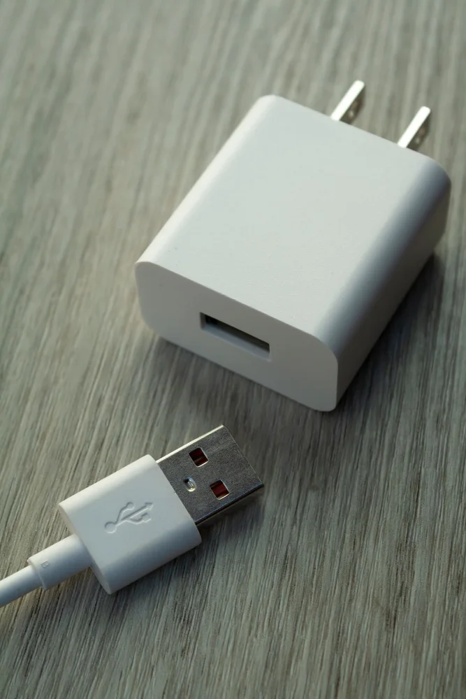 A detailed view of a white USB charger and cable on a wooden surface.