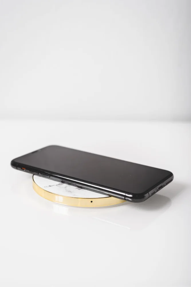 A sleek black smartphone placed on a wireless charger with a modern white background.
