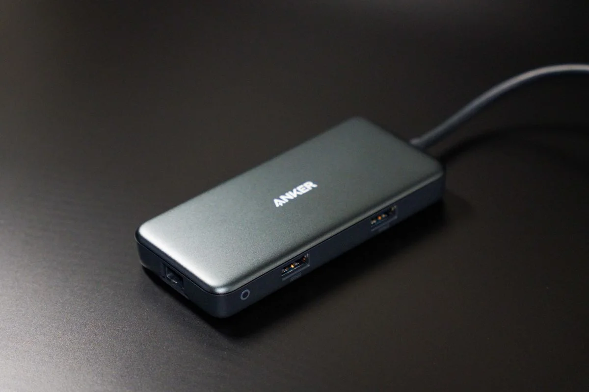 Compact USB-C hub on dark desk surface with visible USB ports.