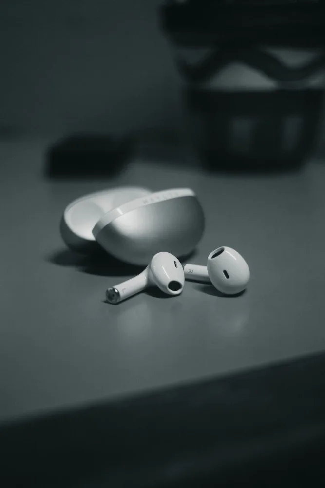 Minimalistic close-up of wireless earbuds with sleek design on a table in monochrome.